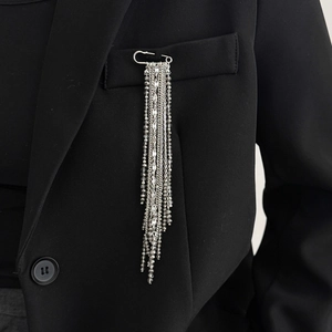 Silver-toned tassel brooch with seed beads and chains pinned on a black blazer