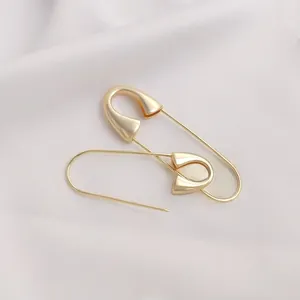 Detail showing high-quality 14K gold plated safety pin earrings on pink fabric