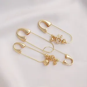 Detailed view of 14K gold plated decorative safety pins with deer and coin charms