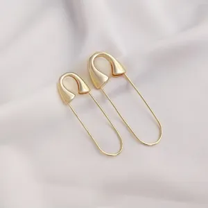 Detailed view of gold plated safety pin earrings on elegant silk fabric background