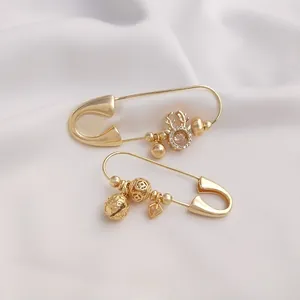 Close-up of 14K gold brooch pins with intricate deer head and textured ball charms