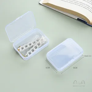 Macro detail of a 9x6x2cm clear plastic organizer box holding a pearl necklace