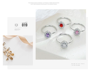 Detailed view of pear-cut zircon rings in red, purple, pink, and white on stone surface
