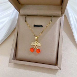 Elegante gouden kersenhanger ketting met rode kralen en zirkoon bladeren op sieradendoos