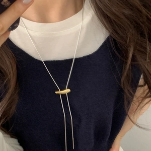 Minimalist two-tone long snake chain necklace with gold pendant on model wearing navy vest