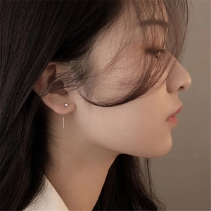 Close-up of a silver minimalist ball stud earring with a sleek vertical bar on female model