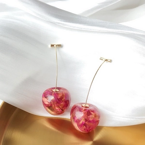 Macro detail of cherry-shaped earring with resin petals and golden metal stem