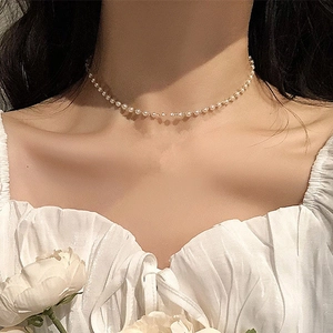 Elegante girocollo di perle bianche con chiusura dorata indossato da una modella