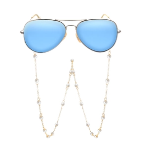 Détail de lunettes pilote aux verres bleu clair miroir et longue chaîne de perles décorative