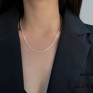 Collier ras du cou minimaliste élégant avec texture argentée porté par un mannequin en blazer
