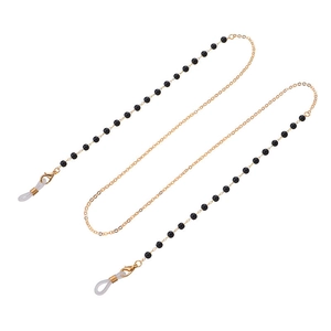 Détail d'une chaîne à lunettes avec fermoirs mousquetons dorés et perles noires sur blanc