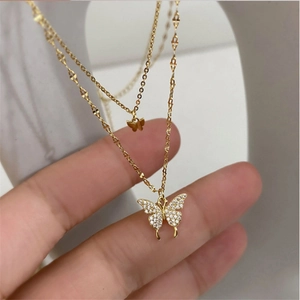 Collier double couche papillon doré avec cristaux scintillants présenté en main
