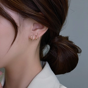 Close-up of four-piece gold earring set with zircon pavé and minimalist hoops worn on ear