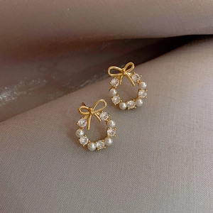 Elegante gouden strikkrans oorbellen met witte parels en zirkonia fonkelende steentjes