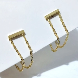 Detail von goldenen Kettenohrringen mit Stab-Design und minimalistisch drapierten Gliedern