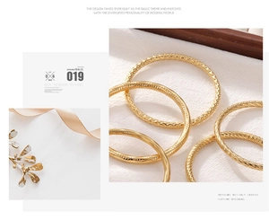 Detail of gold textured bangle set featuring hammered and rope patterns on fabric
