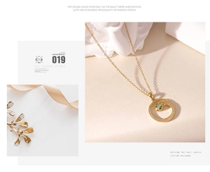 Detailopname van gouden slangenhalsketting met groene edelstenen ogen en witte zirkoniasteentjes