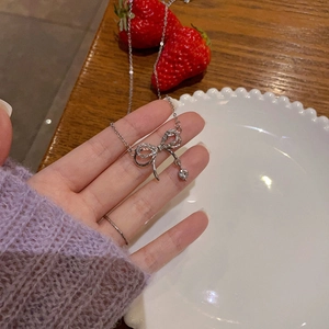 Collier élégant avec pendentif nœud en argent et diamants sur fond de thé chaleureux