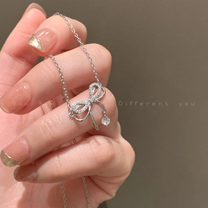 Collier nœud étincelant avec pendentif en zircone sur un fond gris neutre