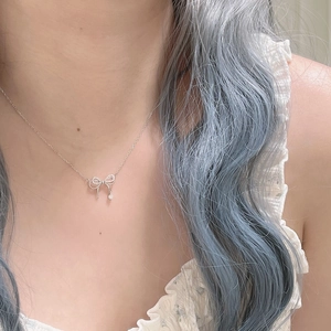 Collier nœud argenté avec pendentif en zircon porté par un mannequin en fleurs