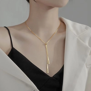 Close-up of minimalist gold triangular geometric lariat necklace on model neck