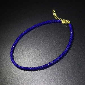 Detail van donkerblauwe kristallen kralen choker met gouden karabijnsluiting en ketting