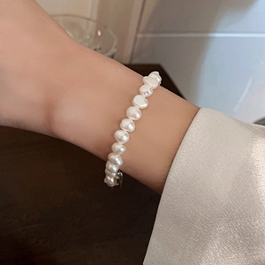 Détail de bracelet en perles de culture baroques sur poignet avec manche en soie