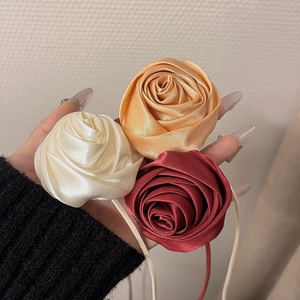Dettaglio di tre accessori a rosa in raso di seta nei colori crema, champagne e bordeaux