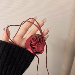 Vista macro di un choker a rosa in raso bordeaux con nastri legati al polso