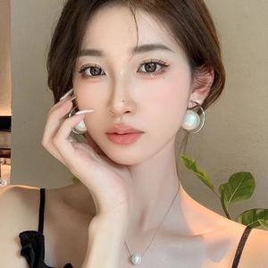 Close-up of oversized pearl hoop earrings and matching necklace set on elegant model