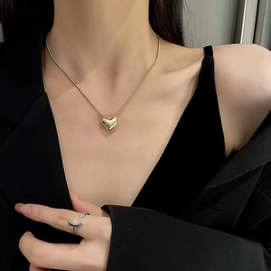 Elegant gold heart pendant necklace and silver open ring set on model with black outfit