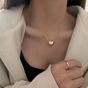 Minimalist gold heart pendant necklace with smooth snake chain on elegant model