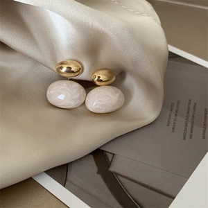 French vintage gold and cream enamel oval stud earrings on an elegant satin fabric background