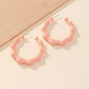 Detailed close-up of large pink bamboo-texture hoop earrings with a matte finish