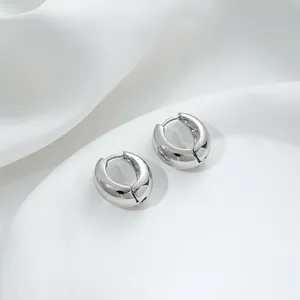 Macro view of silver chunky hoop earrings on white silk fabric with polished finish