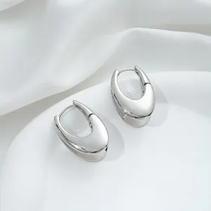 Macro shot of polished silver U-shaped hoop earrings on elegant white satin fabric