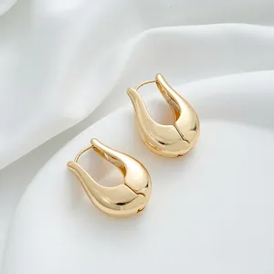 Macro shot of 14K gold-filled water drop earrings on soft white satin background