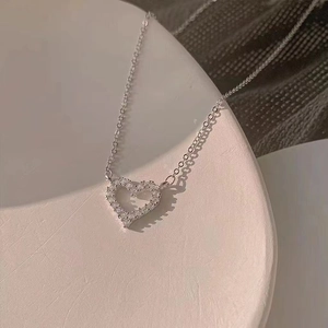Detalle macro del colgante de corazón plateado con piedras de circonita cúbica engastadas