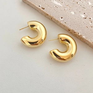 Vue détaillée de boucles d'oreilles créoles dorées en forme de C avec finition miroir polie