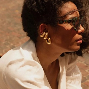 Close-up of chunky gold C-shaped ear cuffs with high-polish metallic finish and modern design