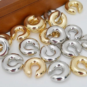 Polished C-shaped ear cuffs in gold and silver finish on a clean white surface