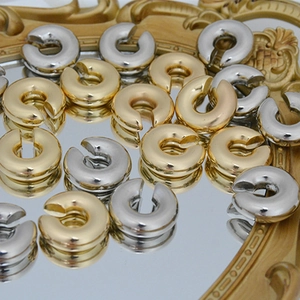 Detailed macro shot of gold and silver C-shaped cuff earrings on a vintage mirror surface