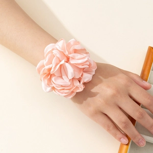 Detailed close-up of a large pink fabric flower accessory worn as a stylish wristband