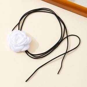 Detailed close-up of a white 3D fabric camellia flower with black velvet cord wrap tie