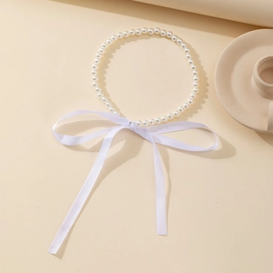 Gros plan d'un collier de perles blanches avec un détail de nœud en ruban de soie