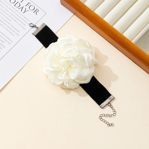 Macro detail of white satin fabric flower choker with black velvet ribbon and silver clasp