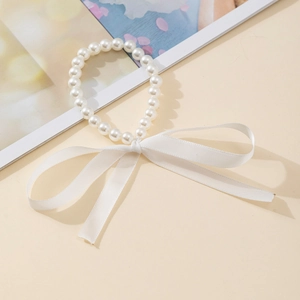 Gros plan d'un élégant bracelet de perles avec un grand nœud en ruban blanc raffiné