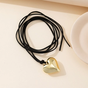 Minimalist long wax cord choker with a golden polished heart pendant on a neutral background