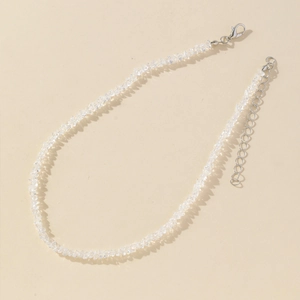 Elegant multi-faceted glass crystal necklace with silver lobster clasp on beige surface