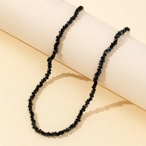 Elegant black beaded necklace with faceted crystals and silver clasp on beige base